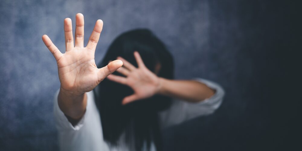 A woman holds her hands away from her face.