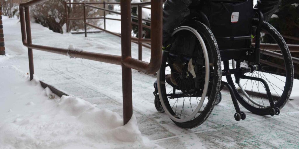 A wheelchair user navigating an icy ramp.