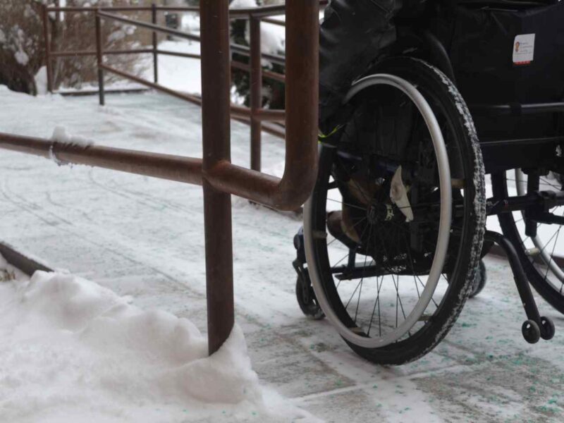 A wheelchair user navigating an icy ramp.