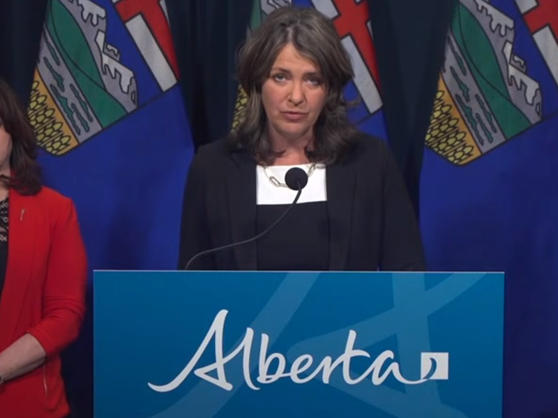 Alberta Premier Danielle Smith talks at a news conference with her health minister, Adriana LaGrange in the background.