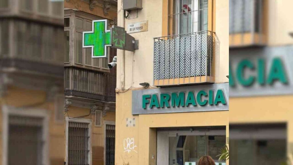 The exterior of a Spanish pharmacy featuring a signature green cross.