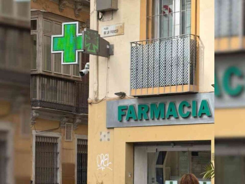 The exterior of a Spanish pharmacy featuring a signature green cross.