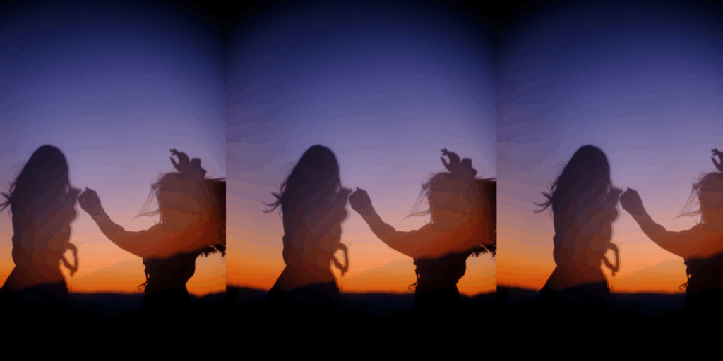 A couple of women dancing in a field.
