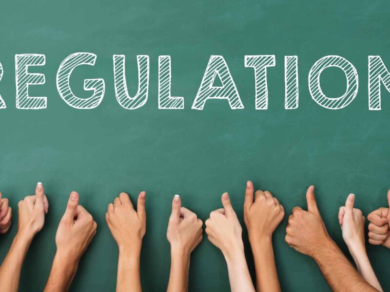 Eight arms giving thumbs up to the word "Regulation" written on a chalk board.