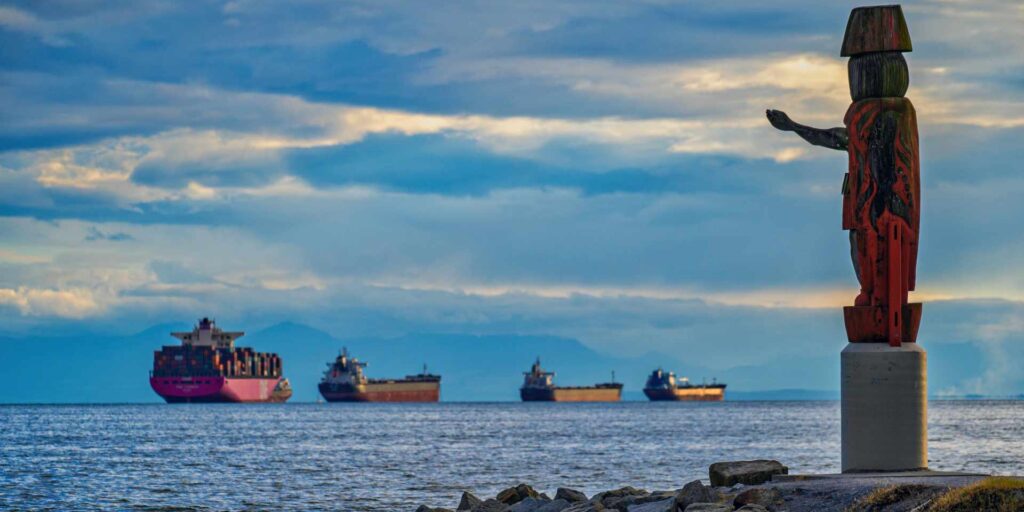 Squamish First Nation Welcome Figure watches cargo ships full of goods off the shores of West Vancouver.