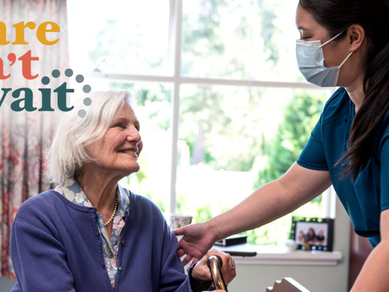 An image of a long-term care worker speaking to a resident. Over the image is text that reads, "Care can't wait." The health employer for B.C. long term care facilities tabled a wage offer that goes up to a 3.5 per cent increase over two years.