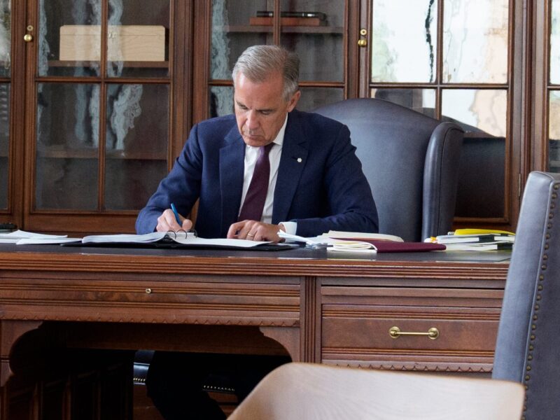 Prime Minister Mark Carney sitting at desk.