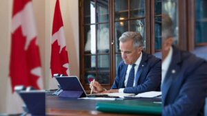 Prime Minister Mark Carney sitting at a desk.