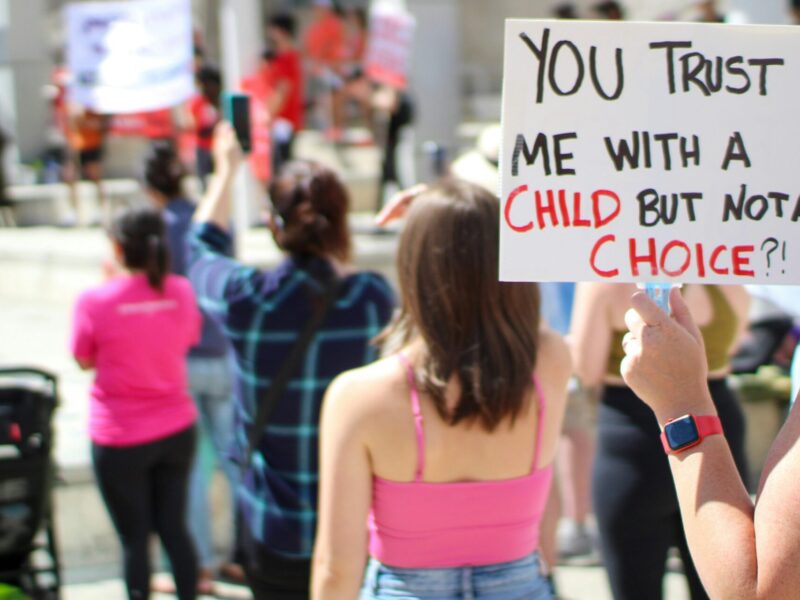 An image of a woman at a protest holding a sign that reads, "You trust me with a child but not a choice?!" An alliance of groups that support reproductive rights is raising the alarm over a recent partnership between Fraser Health and an anti-abortion organization.