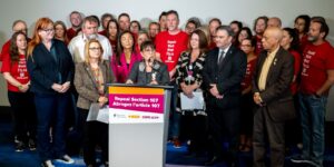NDP MP Leah Gazan surrounded by labour leaders at a press conference announcing legislation to repeal section 107.