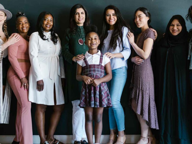 A group of women standing behind a young girl.