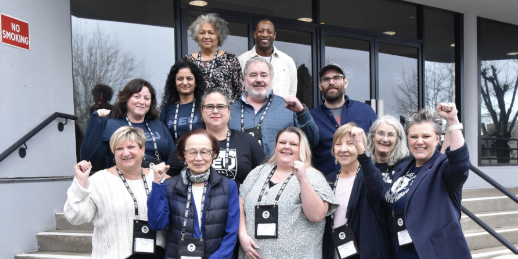 An image of the HEU FBA standing on the steps of the a building raising their fists. The FBA has reached a tentative agreement.