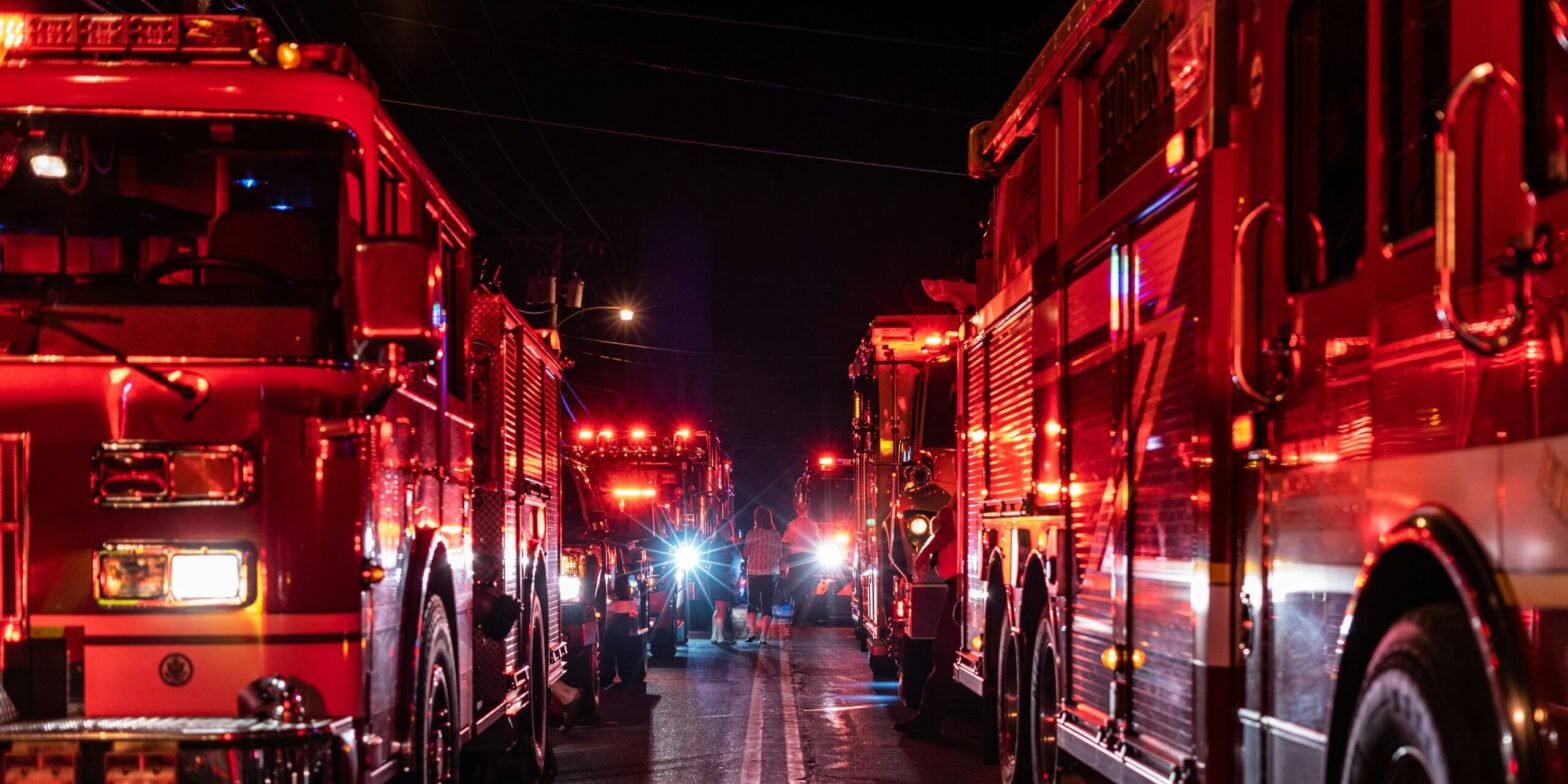 An image of two firetrucks on a dark road with their sirens flashing. Firefighters in a Quebec town are facing sanctions that have soured labour relations.