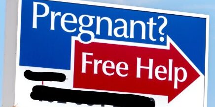 An image of a billdboard for an unregulated pregnancy centre. It reads, "Pregnant? Free Help" with an arrow pointing to the right.