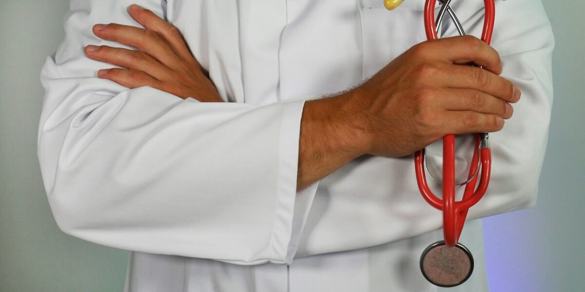A person in a white coat holding a stethoscope.
