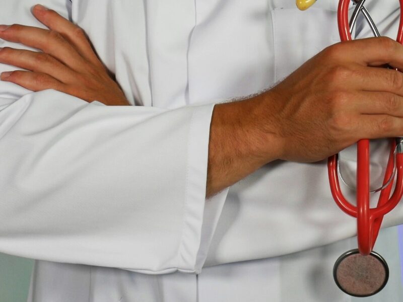 A person in a white coat holding a stethoscope.
