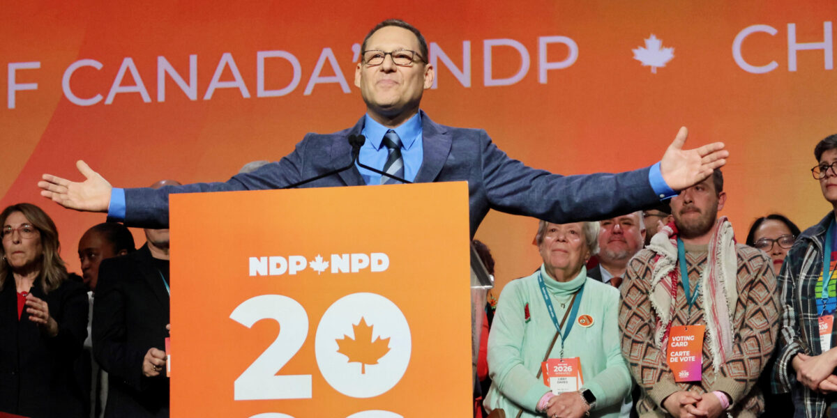 Avi Lewis on the convention stage with supporters behind him after he was announced as the next leader of the federal NPD on Sunday, March 29, 2026.