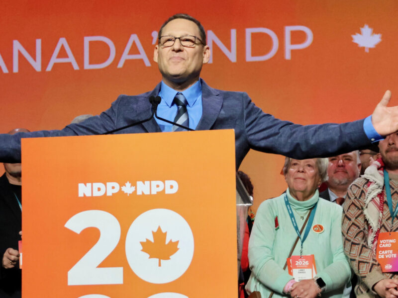 Avi Lewis on the convention stage with supporters behind him after he was announced as the next leader of the federal NPD on Sunday, March 29, 2026.