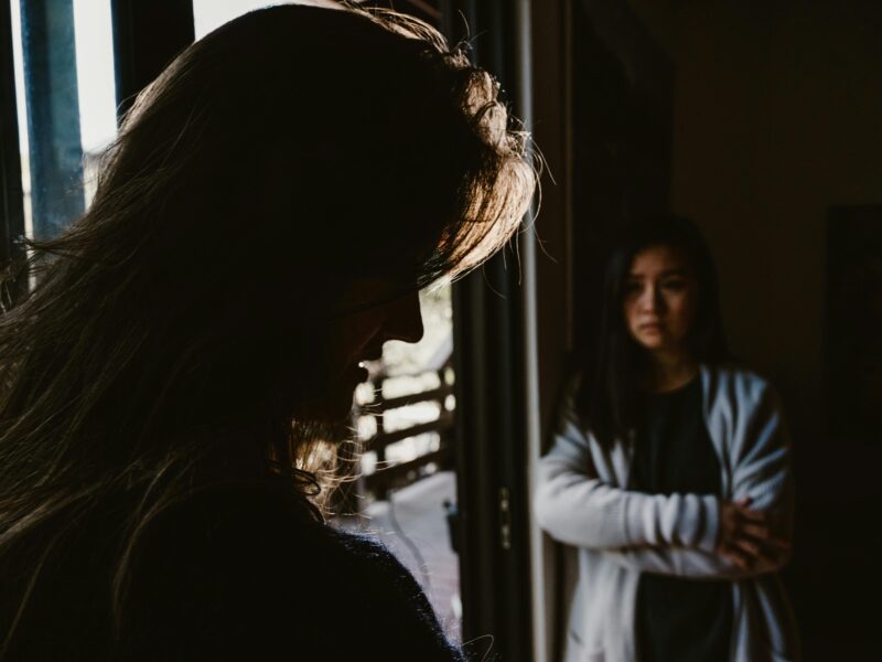 Two women standing in shadows.