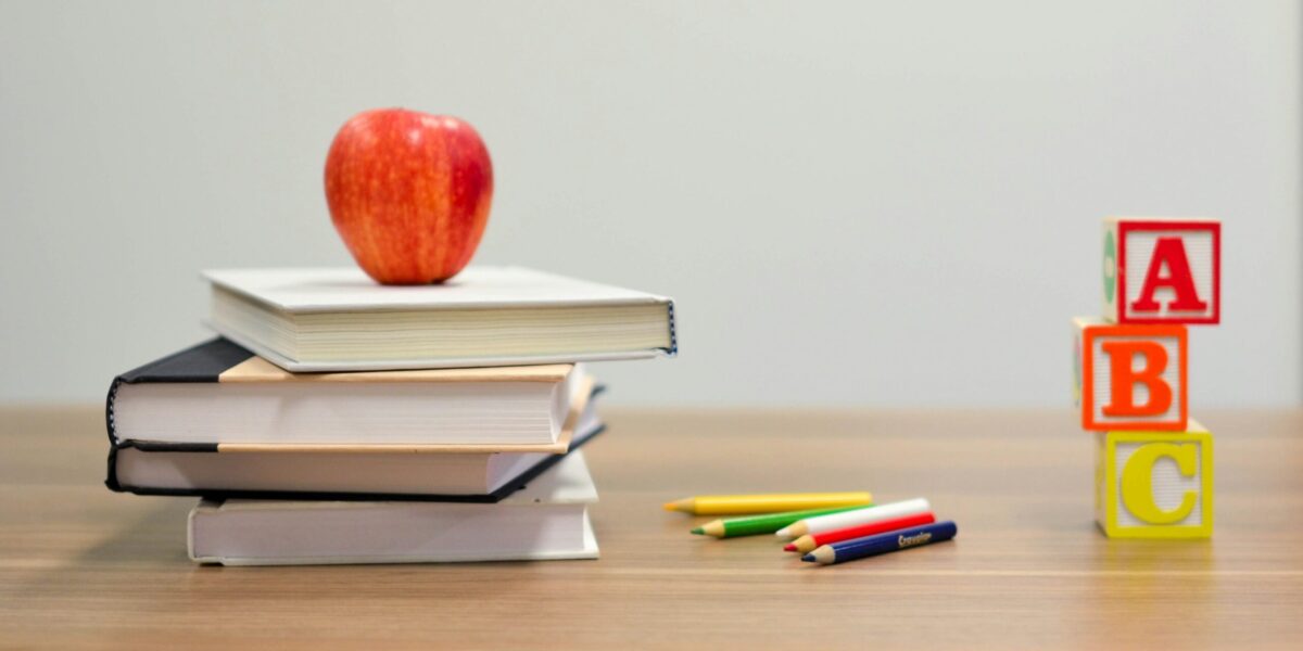 An apple on books next to letter blocks.