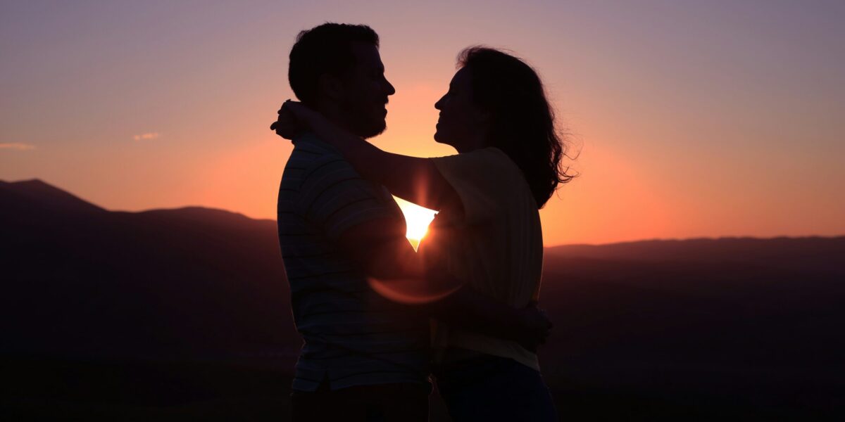 A couple embrace at sunset.