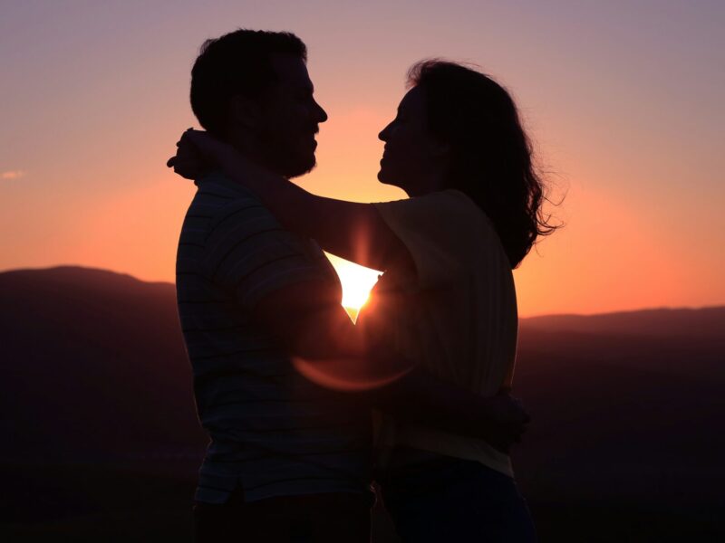 A couple embrace at sunset.