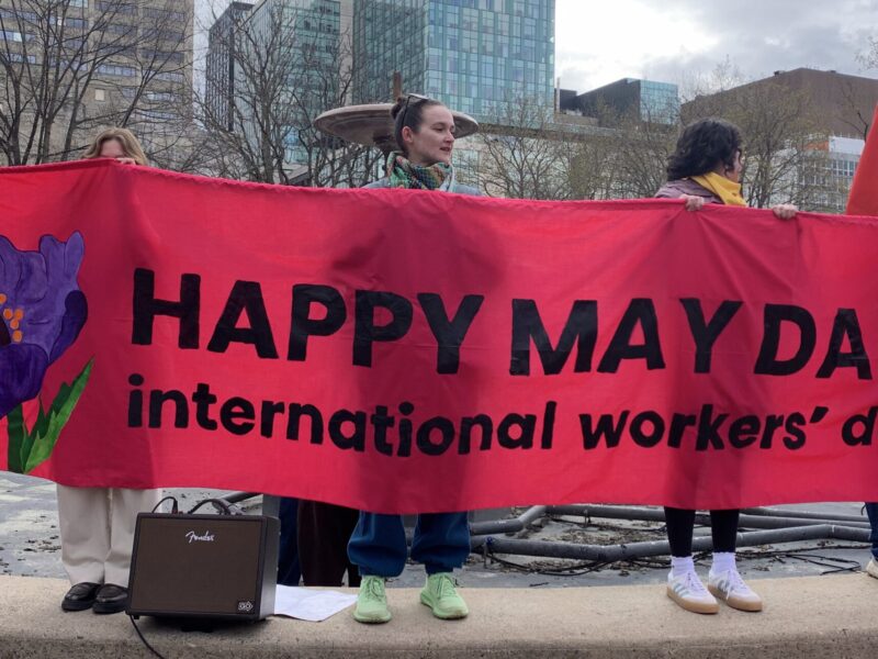 Organizers in Ottawa hold a "Happy May Day" banner as they prepare for their march to begin. Among workers' calls this year was a call against war profiteering and militarism.