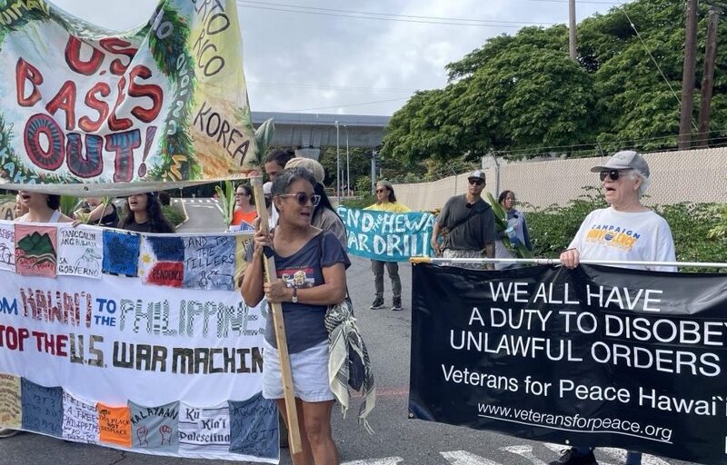 Peace seekers joined Indigenous activists outside Pearl Harbor protesting the occupation of the island and the RIMPAC war games.