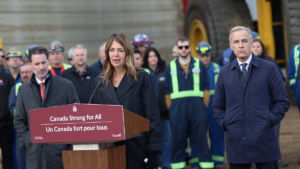 Alberta Premier Danielle Smith, flanked by Pembina Pipeline Corp. CEO Scott Burrows and Prime Minister Mark Carney, at Thursday's announcement about the Pacific Link pipeline project in Fort McMurray.