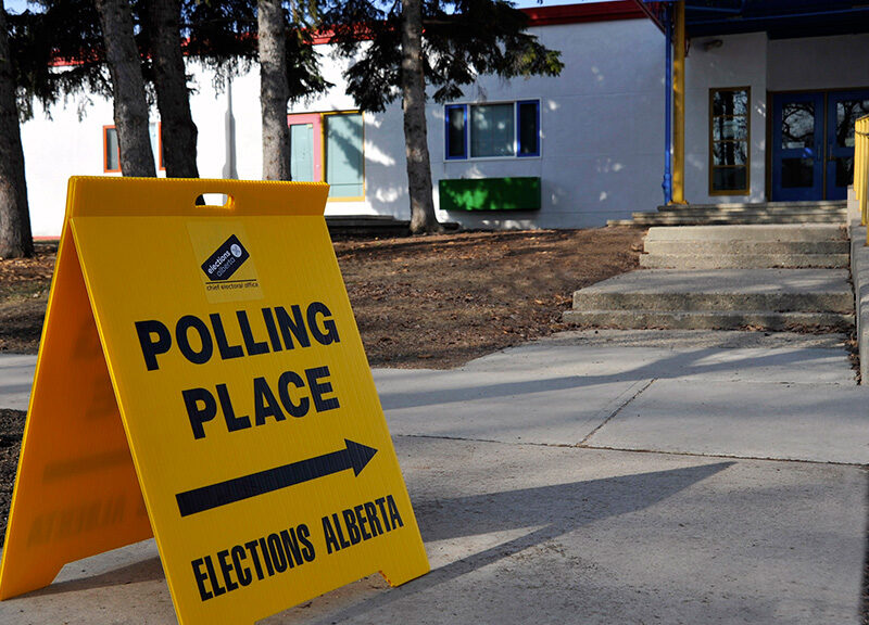 An Elections Alberta sign pointing towards a polling place.