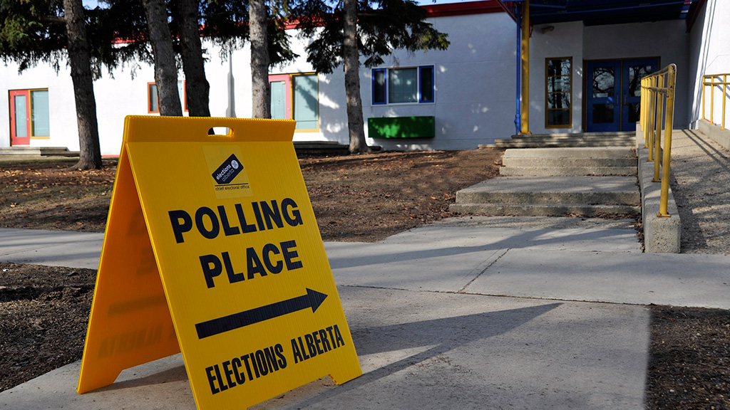 An Elections Alberta sign pointing towards a polling place.